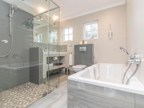 a bathroom with a tub and a shower and a toilet at Whale Rock Luxury Lodge in Hermanus