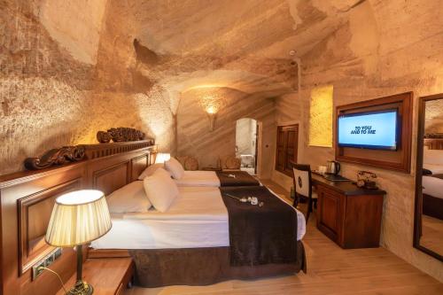a bedroom with a bed and a television in a cave at Utopia Cave Cappadocia in Urgup