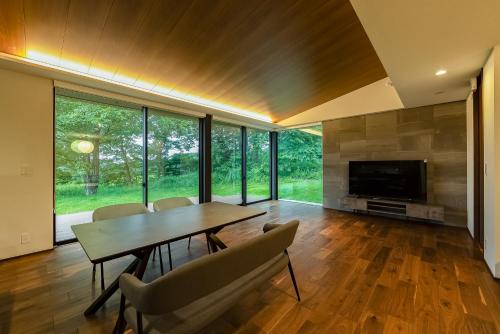 a dining room with a table and chairs and a television at 緑と光が包む家 in Nasu