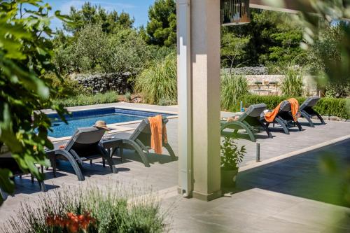 a patio with chairs and a table next to a pool at Luxury Villa Nature with heated private pool, sauna & fire pit, a short walk to the beach in Milna