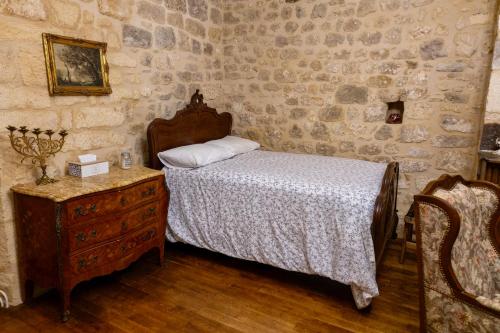 a bedroom with a bed and a wooden dresser with a nightstand sidx sidx at Les Petits Cousins Du Québec - Chambres D’hôtes à Domme in Domme