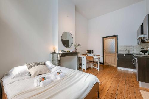 a bedroom with a large white bed and a kitchen at Huswell - Charming studio in the center of Antwerp in Antwerp