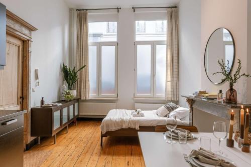 a room with a bed and a table with a mirror at Huswell - Charming studio in the center of Antwerp in Antwerp