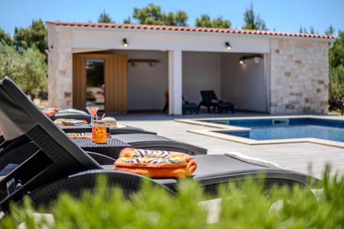 a group of chairs sitting next to a swimming pool at Luxury Villa Nature with heated private pool, sauna & fire pit, a short walk to the beach in Milna