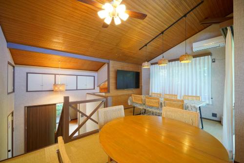 ein Esszimmer mit einem Holztisch und Stühlen in der Unterkunft ファミーユグループ城ケ崎店 空音sorane in Ito