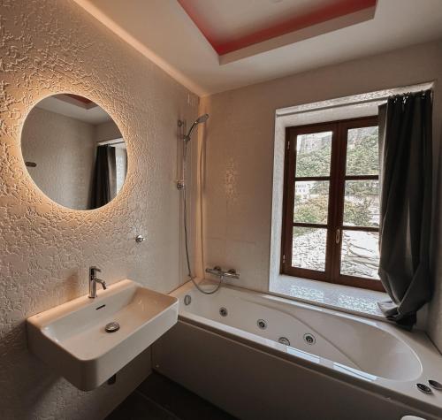 a bathroom with a sink and a tub and a mirror at Kalemi Twin Boutique Hotel in Gjirokastër