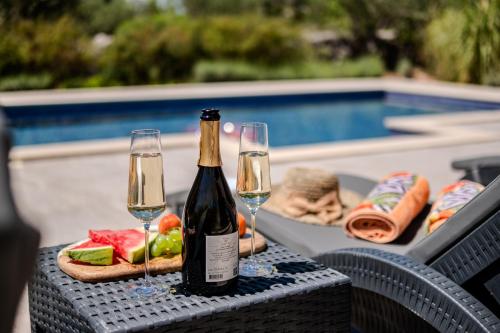 a table with two glasses of wine and a tray of food at Luxury Villa Nature with heated private pool, sauna & fire pit, a short walk to the beach in Milna