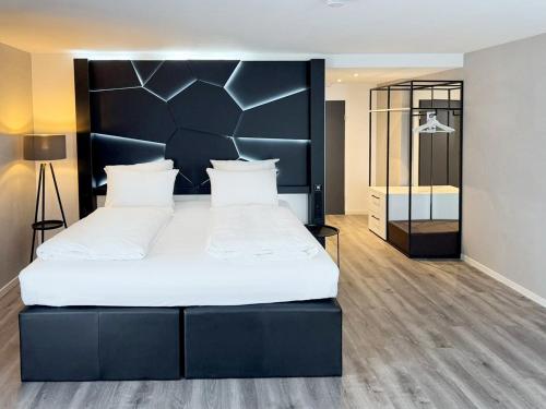 ヴァインガルテンにあるDORMERO Hotel Weingartenのベッドルーム1室(大型ベッド1台、黒いヘッドボード付)