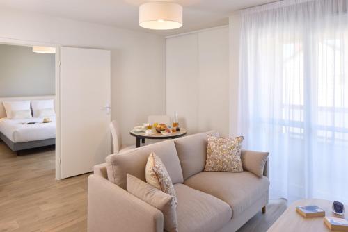 a living room with a couch and a bed at Zenitude Hôtel-Résidences Saumur in Saumur