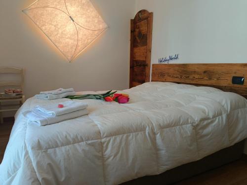 a white bed with towels and flowers on it at Natali Home by Holiday World in Ponte di Legno