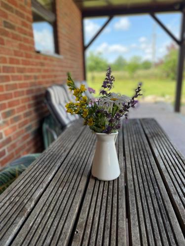 a white vase with flowers sitting on a wooden table at Swallows Retreat in Fordingbridge