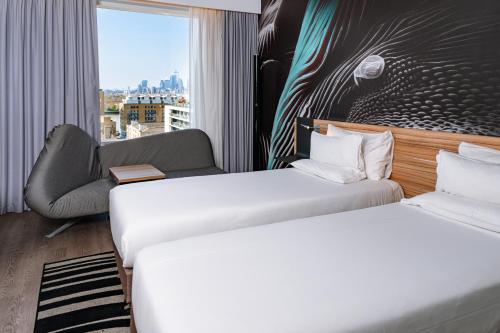 a hotel room with two beds and a chair at Novotel London Canary Wharf in London