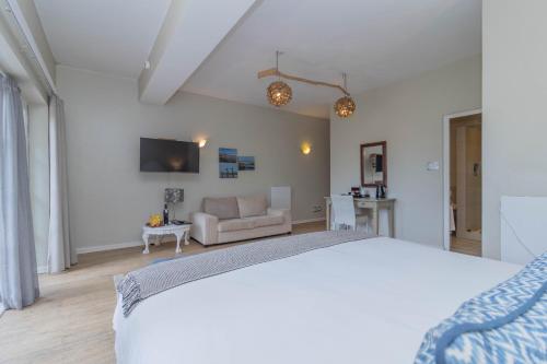 a white bedroom with a bed and a couch at Whale Rock Luxury Lodge in Hermanus