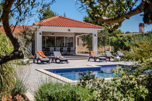 a backyard with a pool and chairs and a house at Luxury Villa Nature with heated private pool, sauna & fire pit, a short walk to the beach in Milna