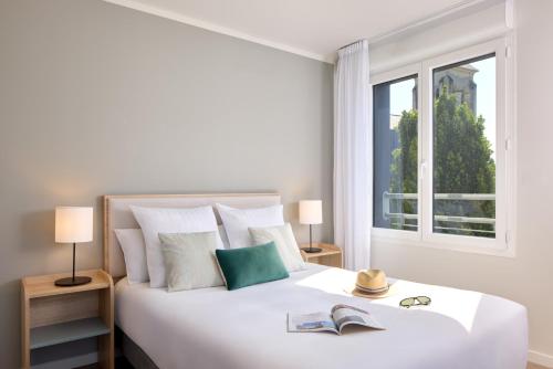 a bedroom with a large white bed with a window at Zenitude Hôtel-Résidences Saumur in Saumur