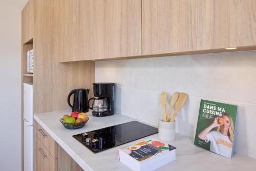 a kitchen counter with a bowl of fruit and a book at Zenitude Hôtel-Résidences Saumur in Saumur