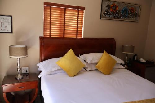 a bedroom with a bed with two yellow pillows at Lakeview Boutique Hotel & Conference Center in Benoni