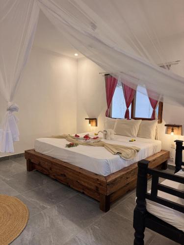 a bedroom with a large bed with a canopy at Paje By Night Bungalows in Paje