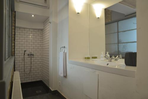uma casa de banho branca com um lavatório e um espelho em Contemporary Acropolis House em Atenas