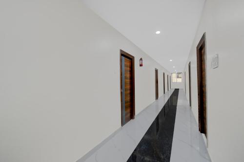 a corridor in a house with white walls and black marble floors at Super Townhouse Oak Bachupally Medical College Formerly SV Hotels in Lingampalli