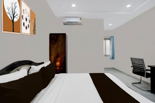 a bedroom with a white bed and a desk at Super Townhouse Oak Bachupally Medical College Formerly SV Hotels in Lingampalli