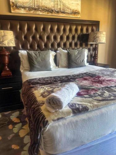 Un dormitorio con una cama grande con un cabecero grande. en Meeting Kingdom Luxury Guest House, en Rustenburg