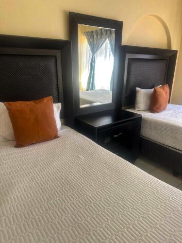 Una habitación de hotel con dos camas y un espejo. en Meeting Kingdom Luxury Guest House, en Rustenburg