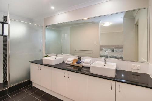 a bathroom with two sinks and a large mirror at 13th Tee by the Sea- On the Golf Course in Dunsborough
