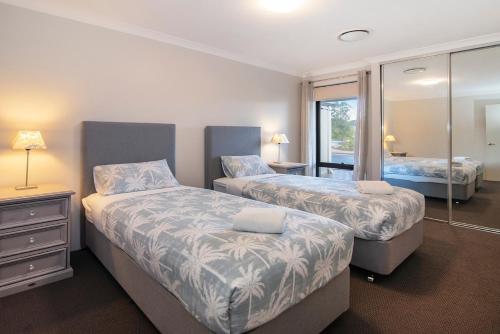 a bedroom with two beds and a mirror at 13th Tee by the Sea- On the Golf Course in Dunsborough