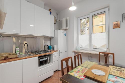 a kitchen with white cabinets and a table with a tableablish at Rynek Nowego Miasta 27 by NYX Apart in Skorka