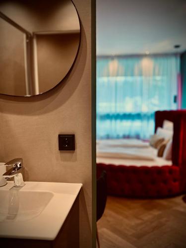a bathroom with a sink and a bed with a mirror at Red Velvet-Romantik Appartement mit Balkon & Flussblick - Das Alpenzeit im Zentrum mit Parkplatz in Bad Aussee