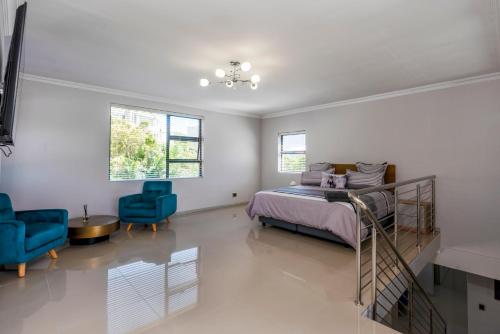 Un dormitorio con una cama y dos sillas azules. en Villa Summer Classic, en Hout Bay