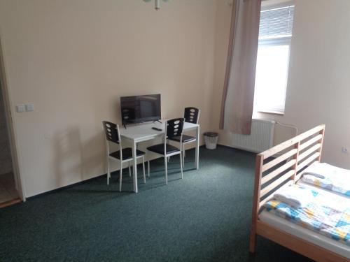 a room with a desk with chairs and a television at Hotel U Lázní - ubytování pro nenáročné in Ostrožská Nová Ves