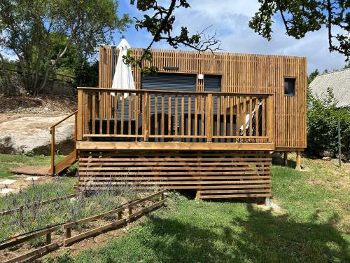 a wooden house with a deck in a yard at Lou Mazet Séjour en Aubrac in Saint-Laurent-de-Muret