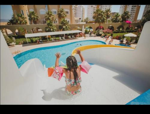 a little girl standing on a slide by a swimming pool at Caesar Resort studio in Iskele