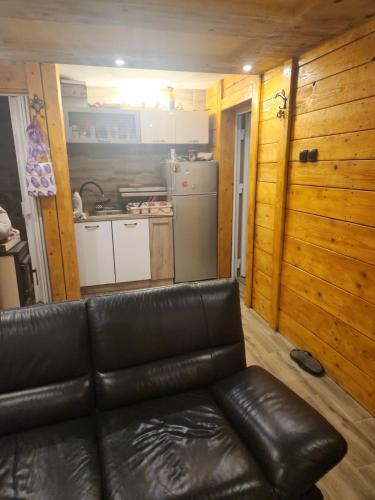 ein Ledersofa im Wohnzimmer mit Küche in der Unterkunft Kuća sa Pogledom in Sremski Karlovci