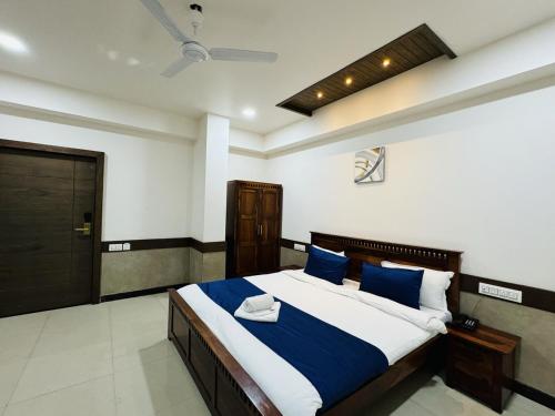 a bedroom with a large bed with blue and white pillows at Col's Hotel Uphaar Tirth in Ujjain