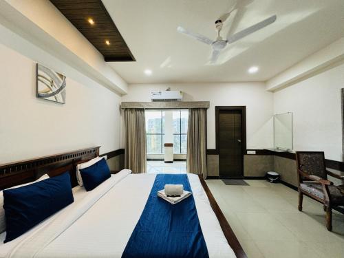 a bedroom with a large bed with blue pillows at Col's Hotel Uphaar Tirth in Ujjain