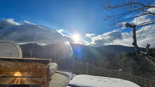 a snow covered igloo with the sun in the background at La Bulle d'Ardèche in La Chanal