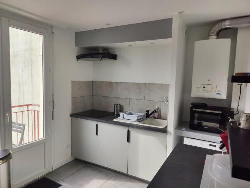 a kitchen with white cabinets and a sink at T4 coeur de ville, à deux pas de la plage - 3 chambres in Saint-Nazaire