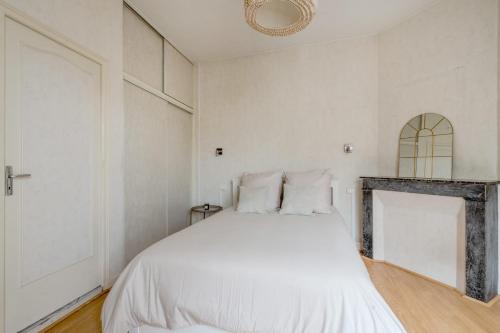 a white bedroom with a bed and a fireplace at La Ferté - Wifi - Animaux autorisés in La Ferté-Bernard