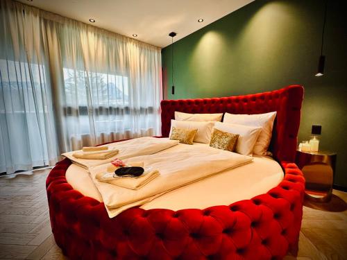 a large bed with a red headboard in a bedroom at Red Velvet-Romantik Appartement mit Balkon & Flussblick - Das Alpenzeit im Zentrum mit Parkplatz in Bad Aussee