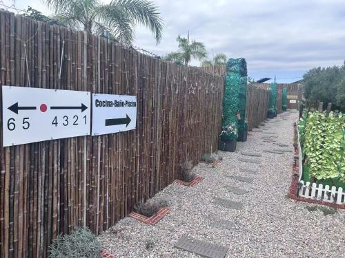 a fence with a sign on it next to a fence with plants at J&L Glamping in La Presa