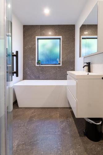 a bathroom with a tub and a sink and a window at Urban Nest on Perth 3BR 1 and a half Bath Free Parking in Christchurch