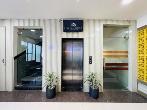 a building with two potted plants in front of a door at Col's Hotel Uphaar Tirth in Ujjain