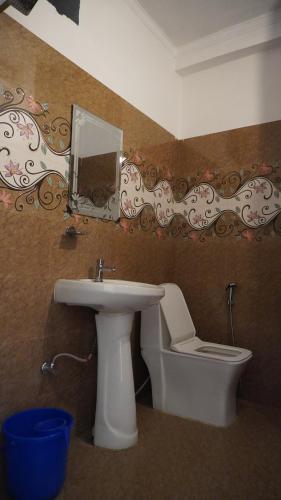 a bathroom with a sink and a toilet and a mirror at Hari Om Guest House in Narendranagar