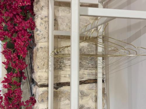 a glass staircase in front of a stone wall with flowers at Casa Palma Boutique Hotel in Vlorë