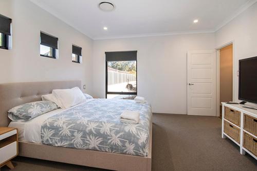 a bedroom with a bed and a flat screen tv at Tidal Wave Hideaway in Broadwater