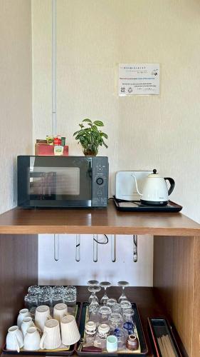 a microwave sitting on top of a shelf next to cups at ふる郷荘Furusato Furano in Furano