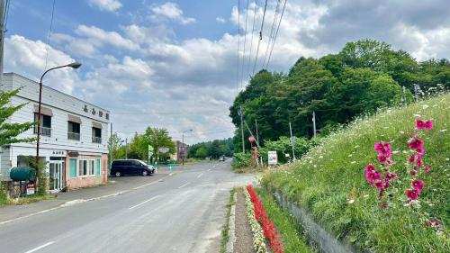an empty street with flowers on the side of the road at ふる郷荘Furusato Furano in Furano